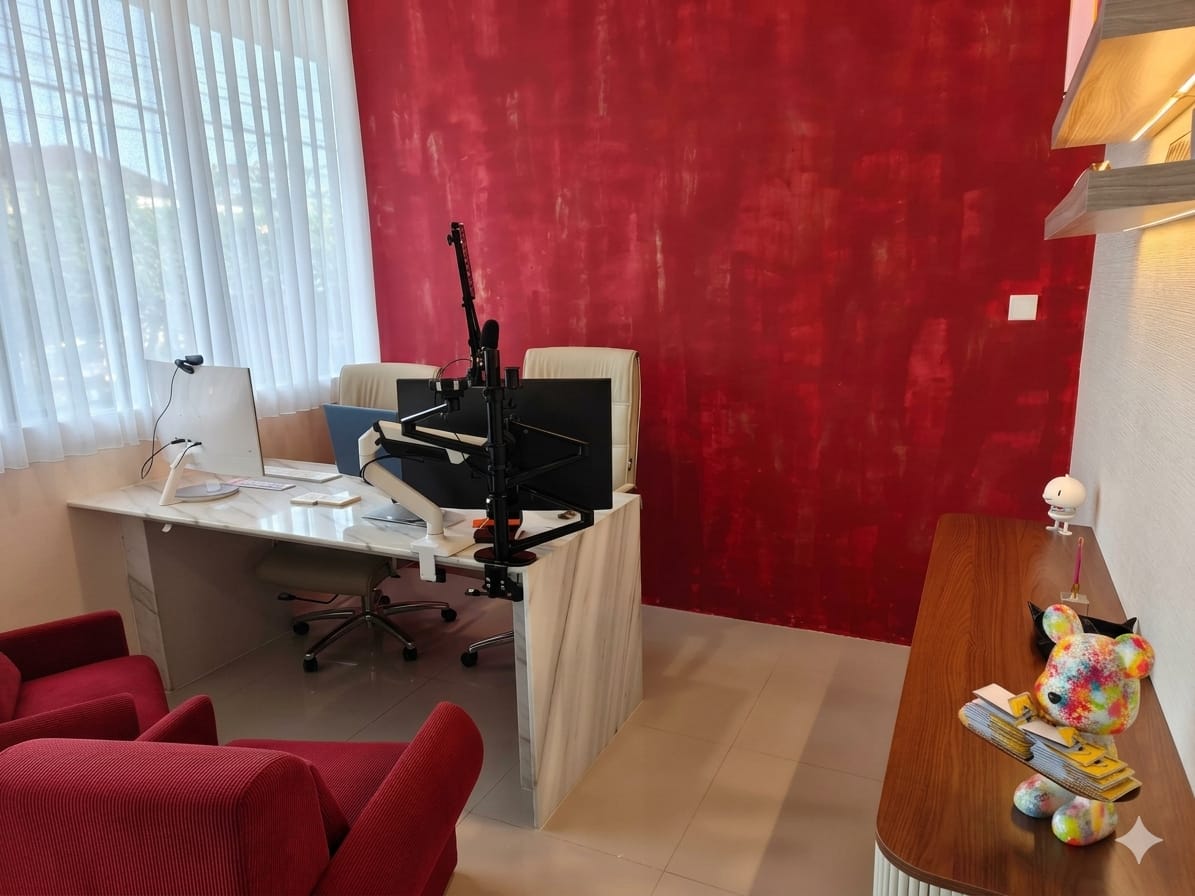 The Office — a professional office-style studio with a large desk, dual monitors, a red corduroy accent chair, and a crimson textured accent wall