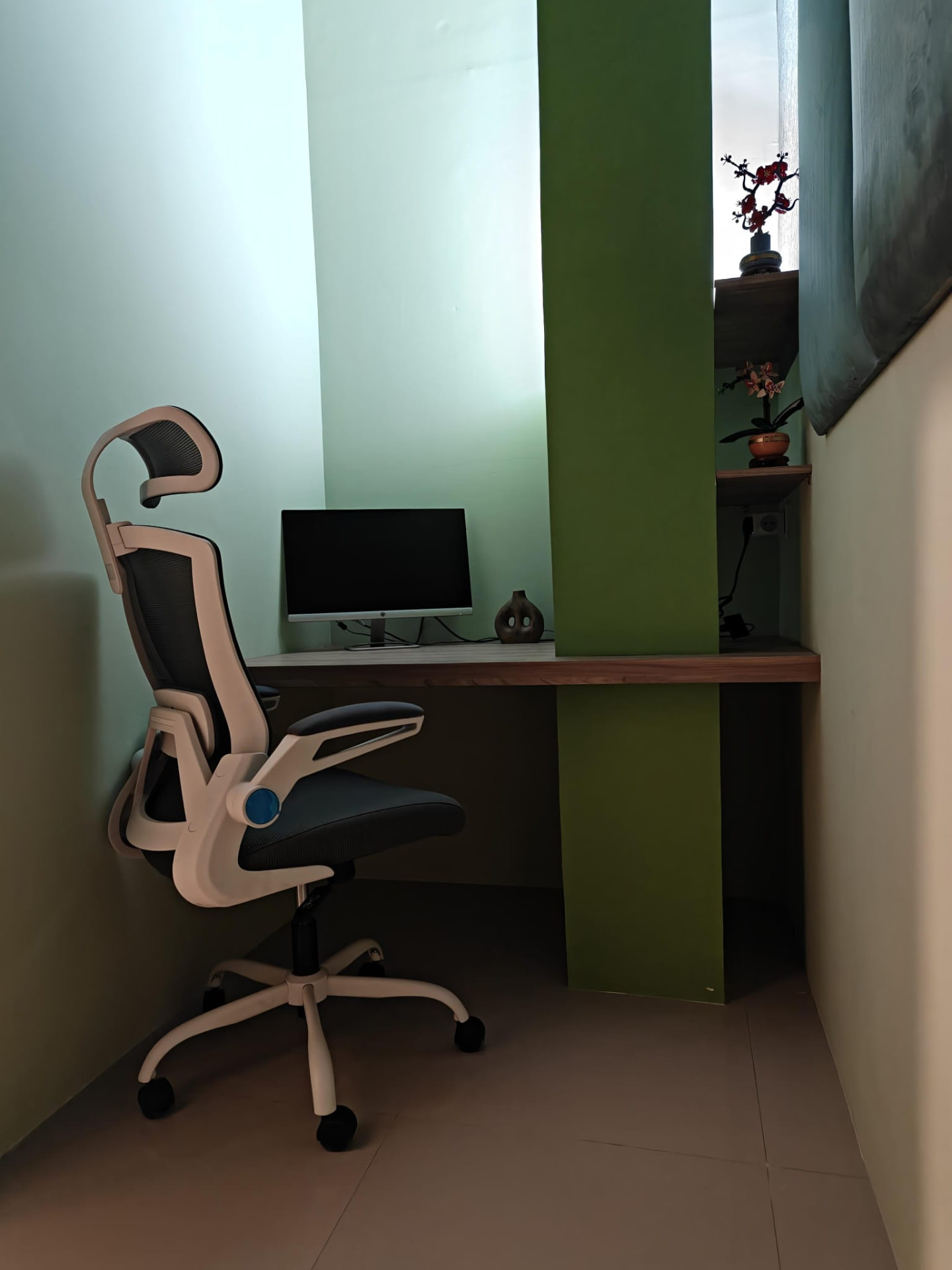 The Green Room — a compact, sound-treated solo studio with a floating desk, ergonomic chair and shelving against a soft green wall